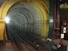 Un túnel de ferrocarril de vía estrecha con una sola vía de ferrocarril, iluminado por una luz blanca brillante