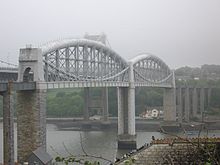 un puente sobre un río en un alto nivel, la cubierta del puente apoyado en el centro por vigas tubulares de metal curvadas